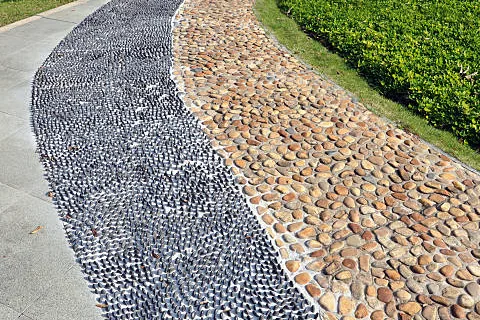 An acupressure path of river pebbles beside a hedge at Sylvia City